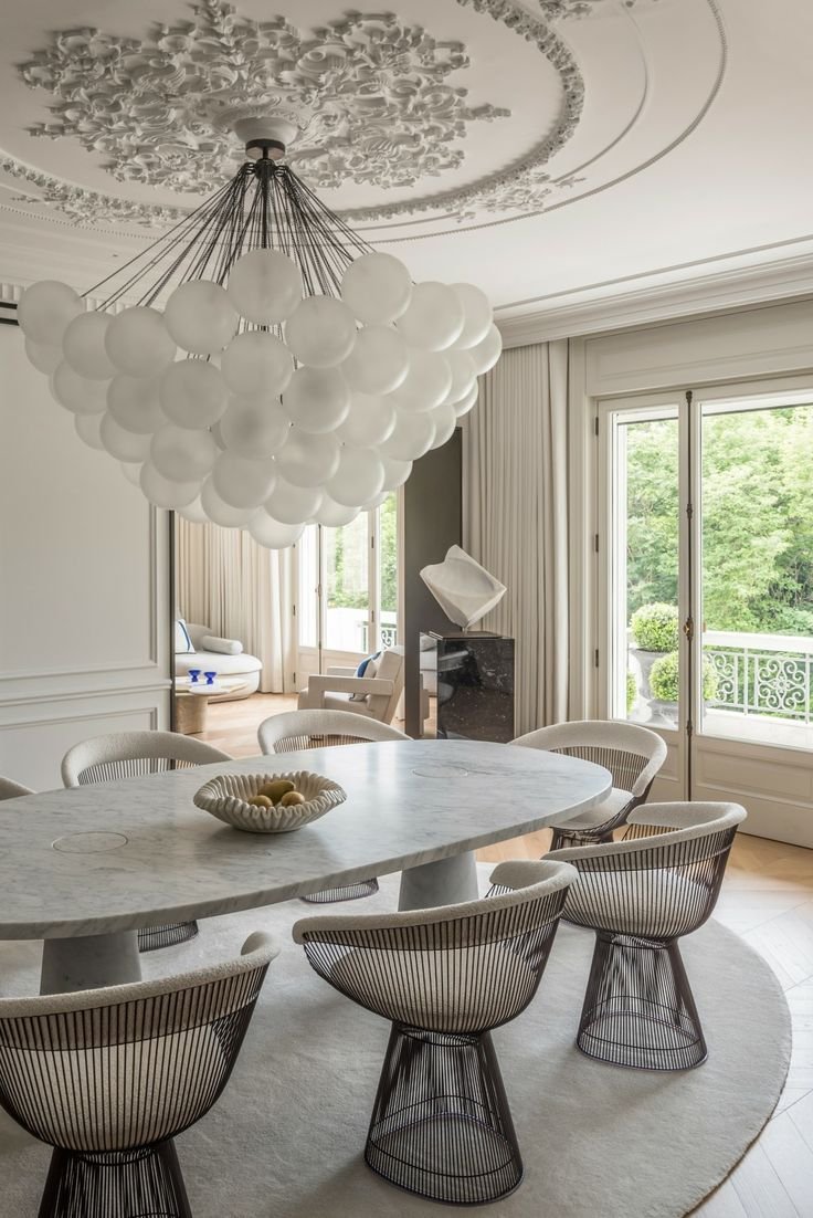 Palm Beach luxury interior designed with European principles and timeless coastal materials. This luxury modern dining room has  European sensibility combined with mid century modern elements, including the iconic steel chairs.