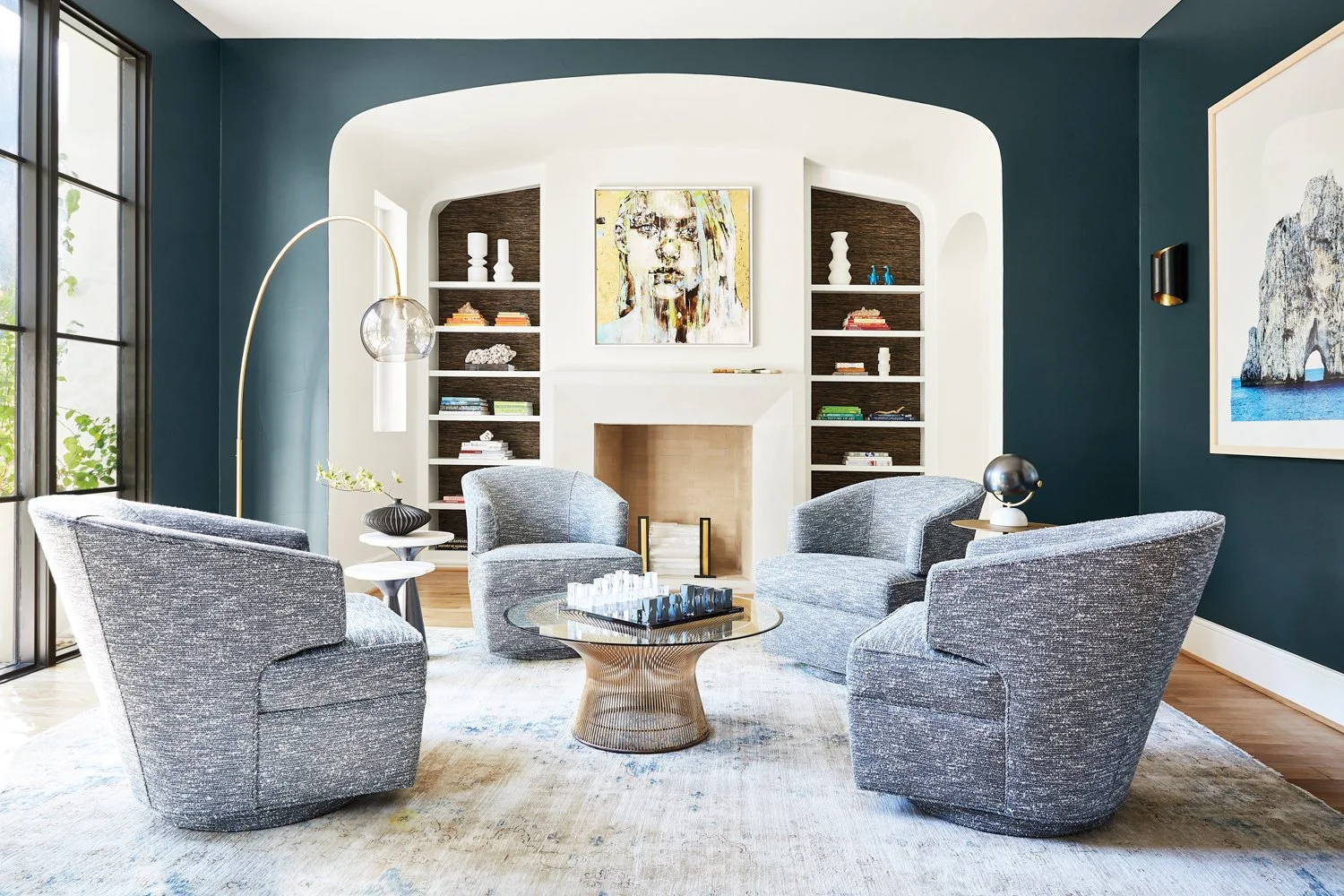 Timeless Palm Beach sitting room with blue swivel chairs, built ins, striking art, and deep blue walls.