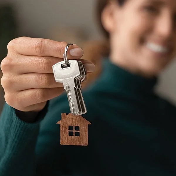 New homeowner holding house keys with small home keychain
