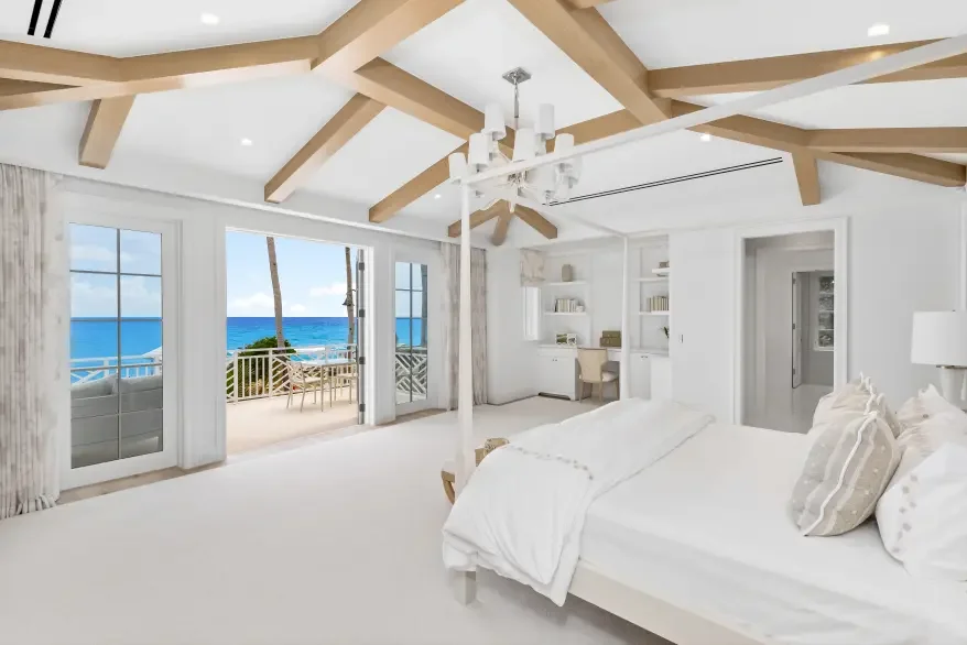 Bright coastal luxury Palm Beach primary suite with wood beams and sea views