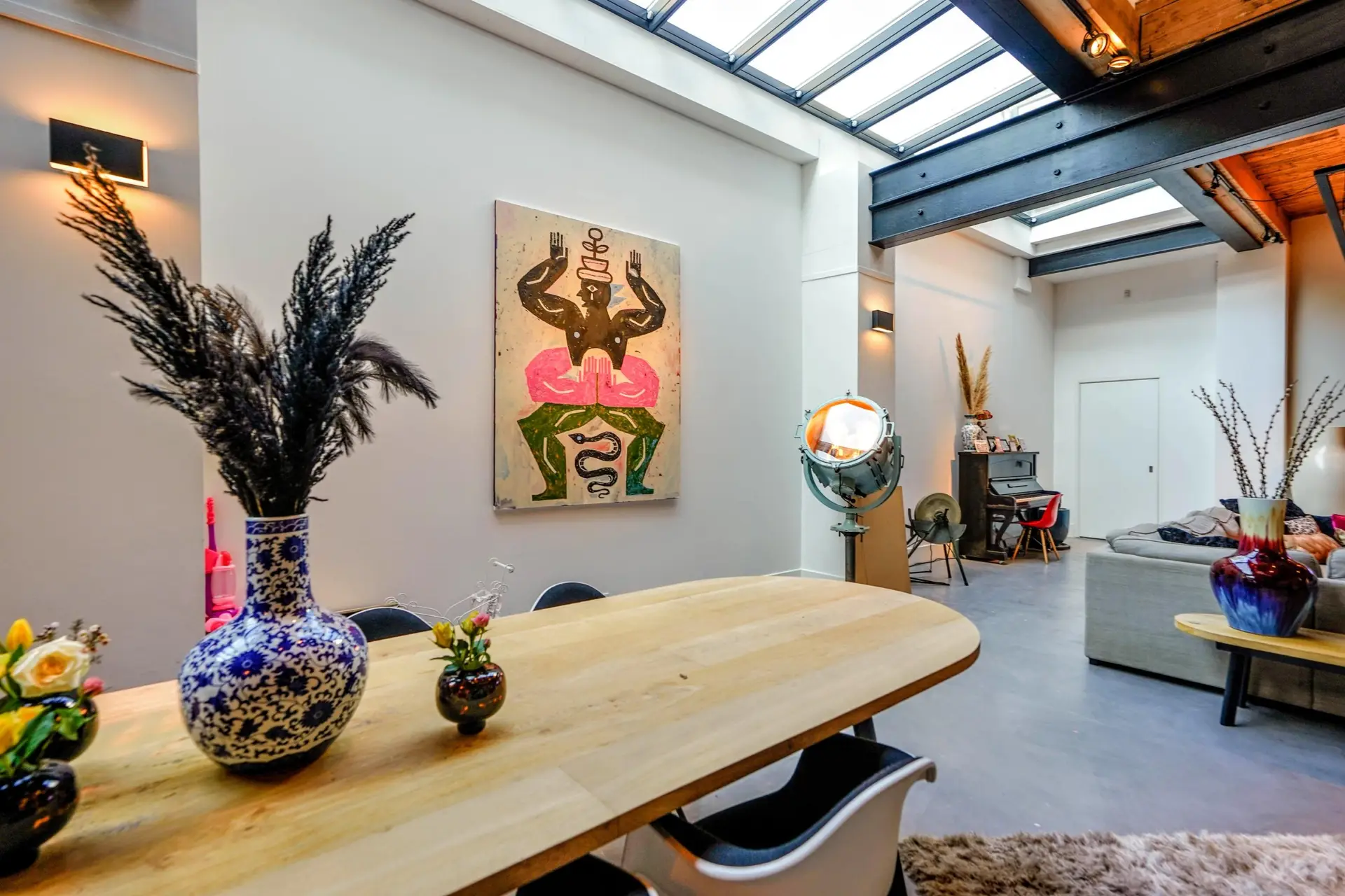 Dutch dining room with wood table, skylight, and modern art emphasizing natural light and simple European interiors.