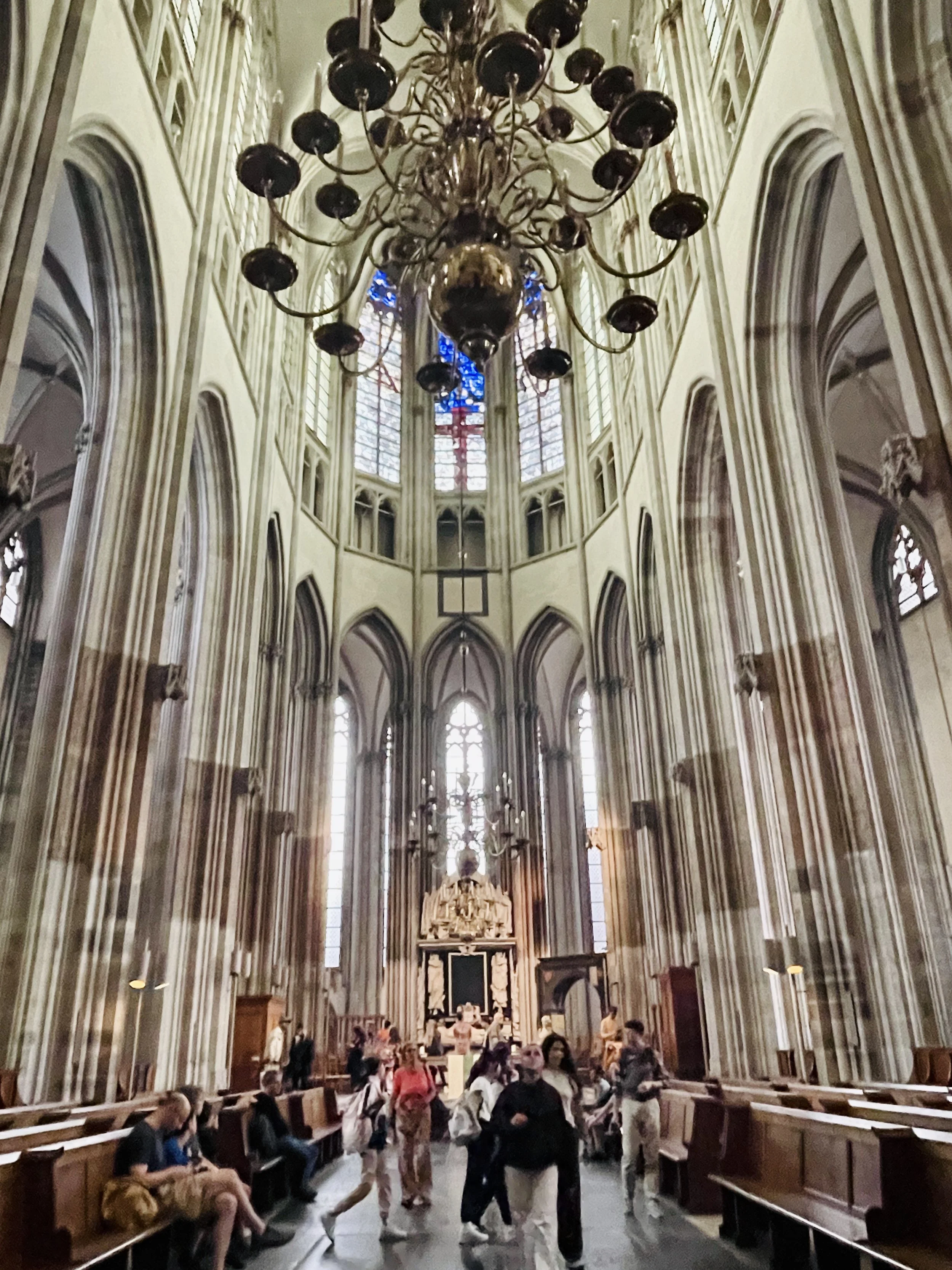 An aisle between pews of the Utrecht Domkerk with chandelier above.