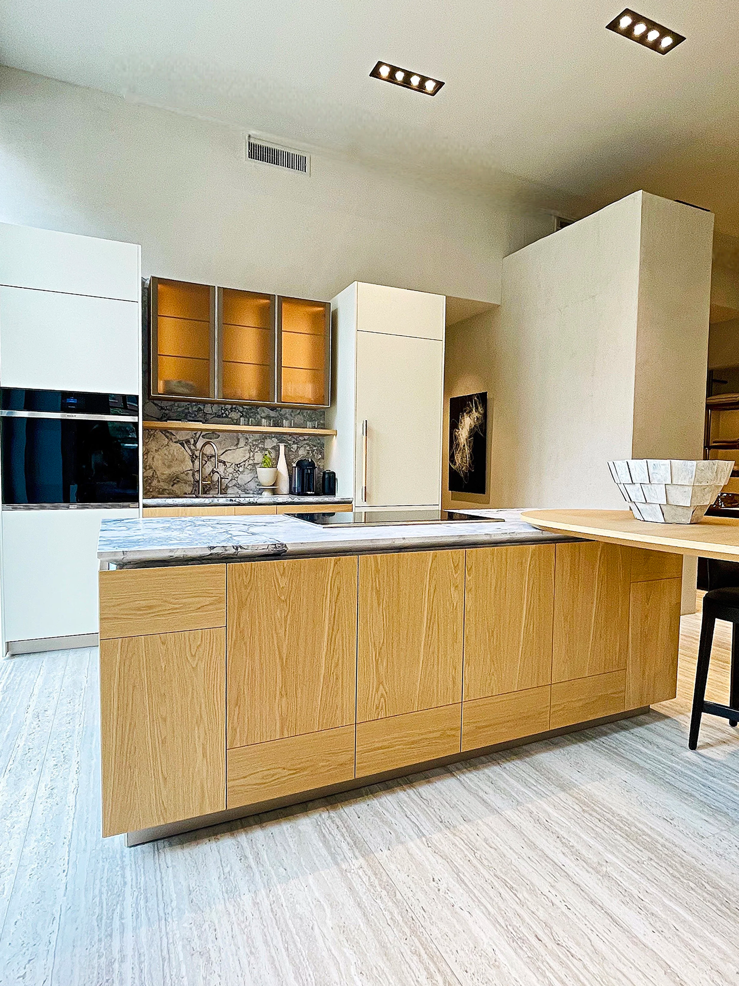 Palm Beach custom built kitchen in Italian light oak and vanilla paint has bold diagonal marble countertops and surfboard peninsula.