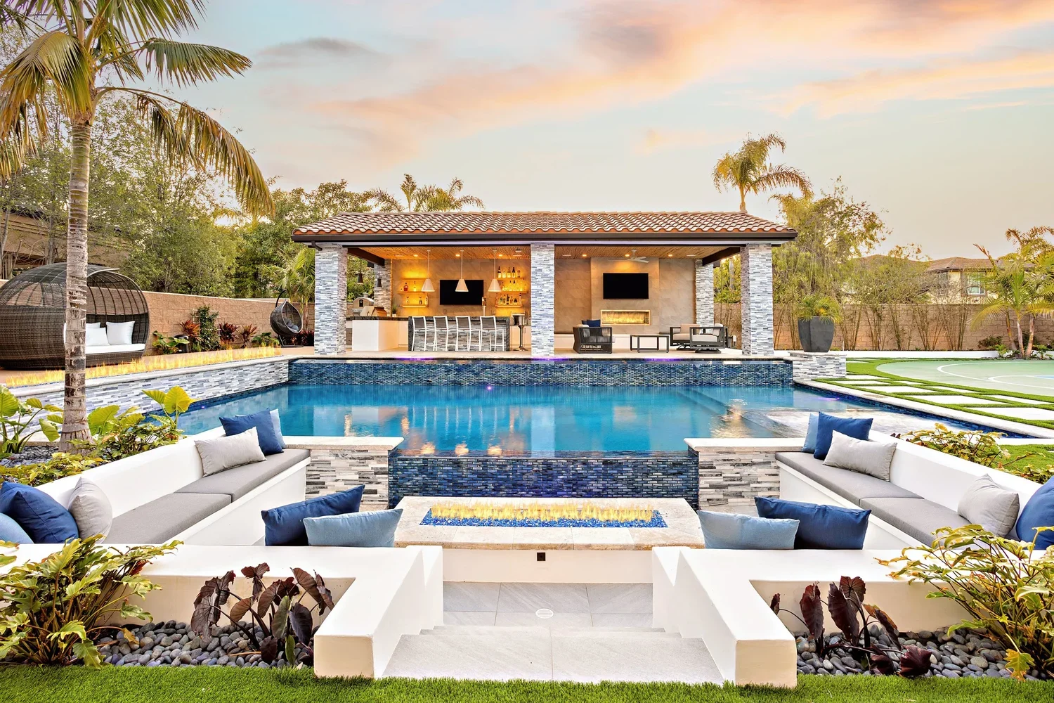 Resort-style luxury backyard with pool, fire pit, and outdoor kitchen
