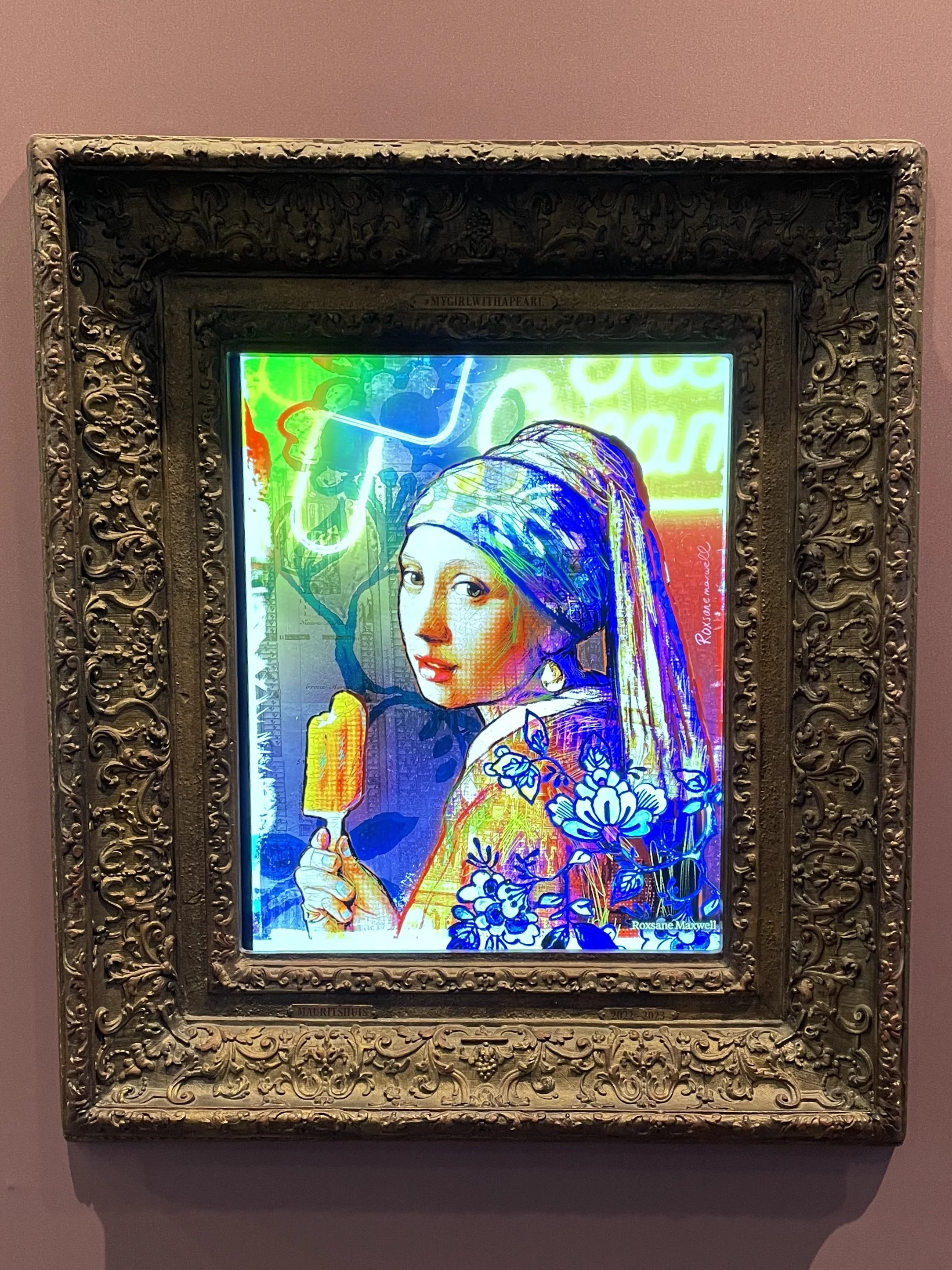 Contemporary neon artwork inspired by Girl with a Pearl Earring in ornate gold carved frame on mauve wall.