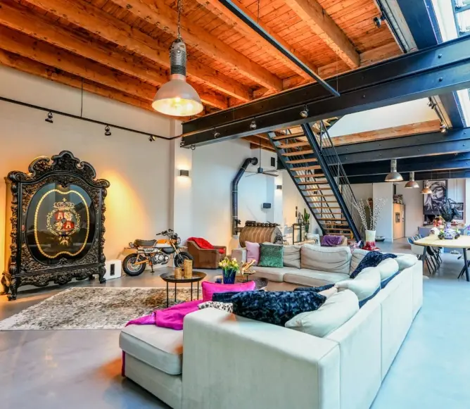 Dutch industrial loft living room with exposed beams, large sectional sofa, colorful accents, and statement cabinet.