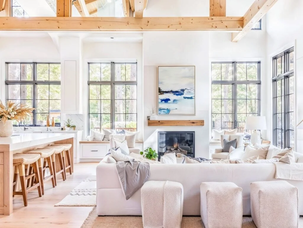Bright rustic coastal great room with beams and light sofas, neutral warm layered textiles with oak wood floors.