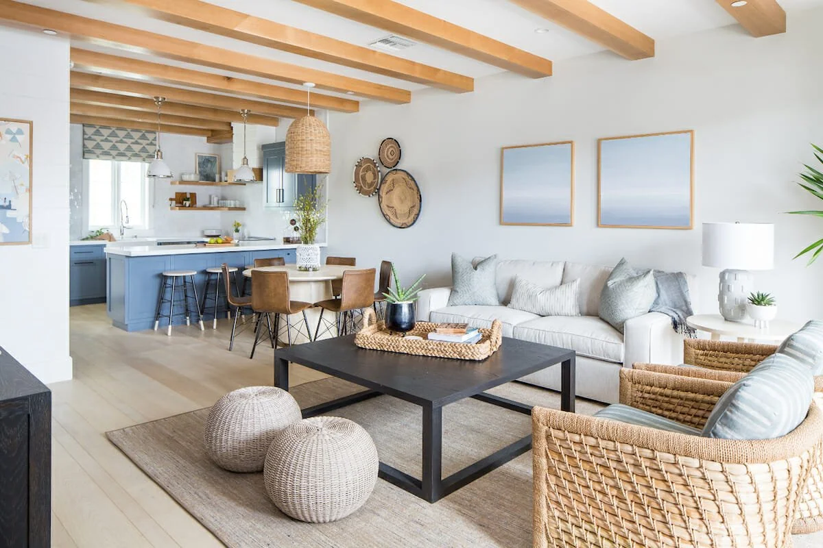 Open-concept coastal living room with woven furniture, neutral sofa, and blue-accent Palm Beach kitchen.