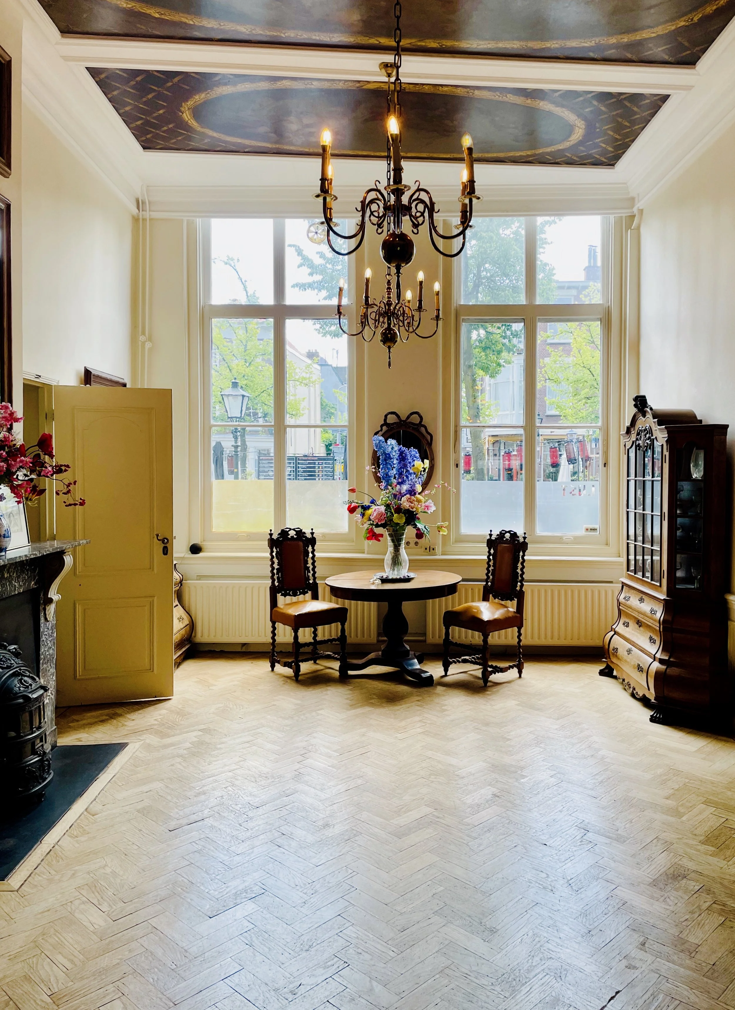 A Dutch Salon from 1649, simply decorated, it features a painted and gilded ceiling, simple lighting, pale oak herringbone floors, and a welcoming view through the large windows overlooking the canals.