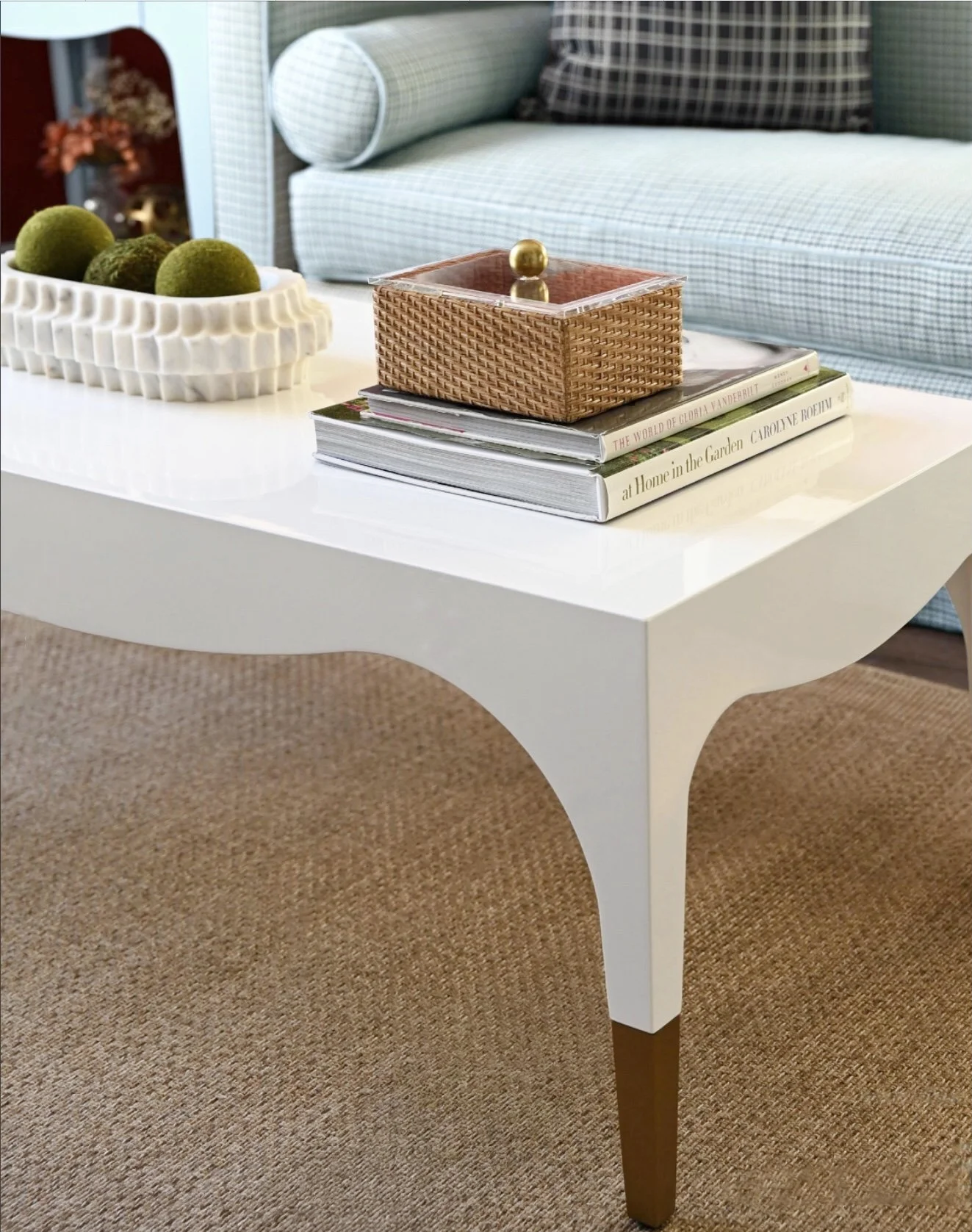 A full-Service Luxury Interior Design project shows a detailed closeup of a white cocktail table in front of a bespoke sofa and with beautiful accessories, showing the beauty of timeless style.