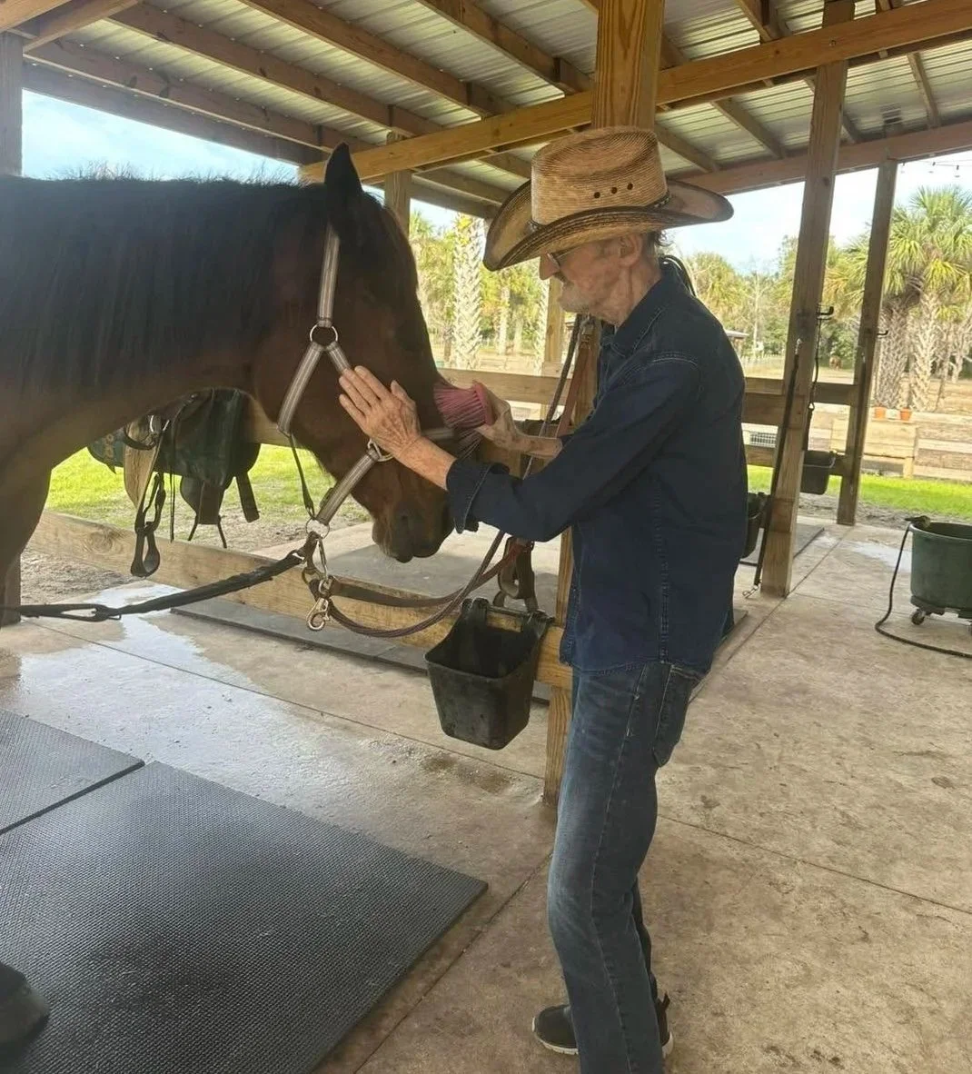 Curt, 94, brushing a horse in the barn during a Horse Experience at Hidden Palms Ranch