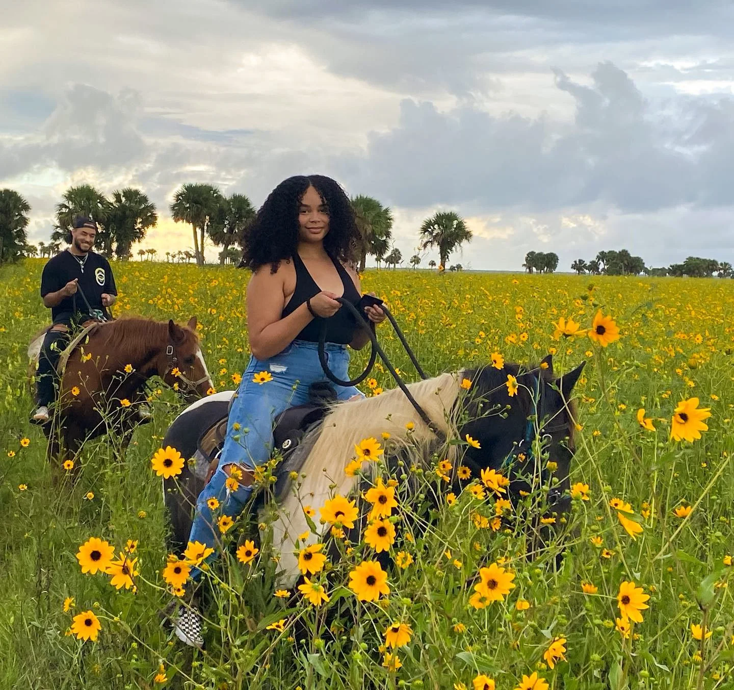 Two riders on horseback in the swamp sunflowers under an evening sky
