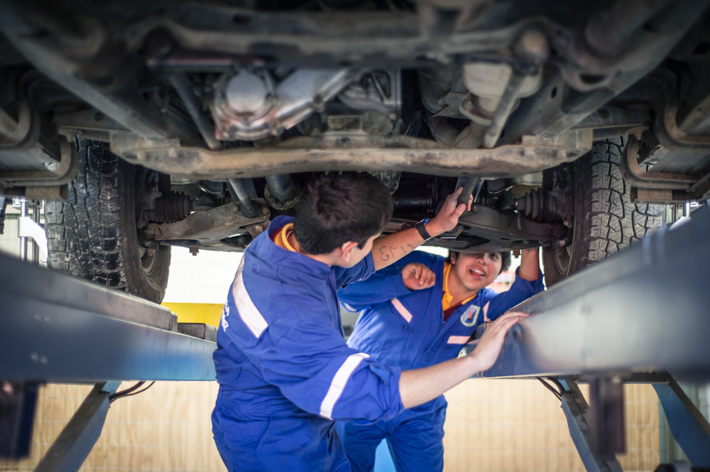  Two of Jose Luis’s students explore the underside of a car. 