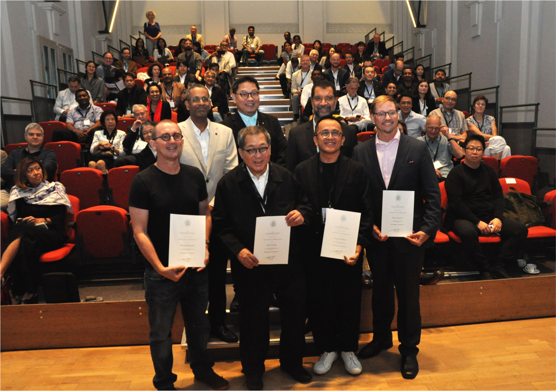 Presenters with conference participants in the background.