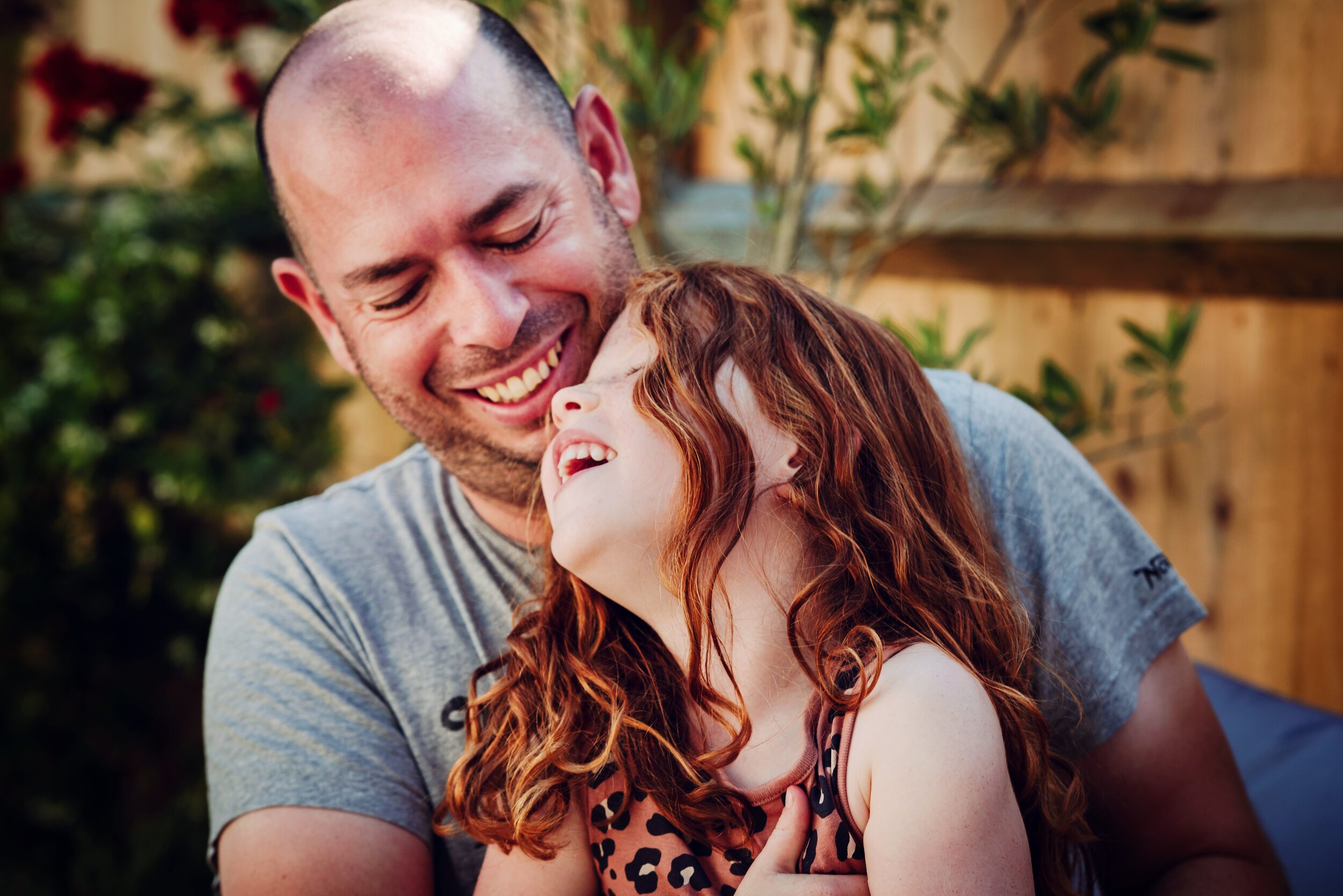 A man and young girl sharing a joyful moment outdoors, smiling and laughing.
