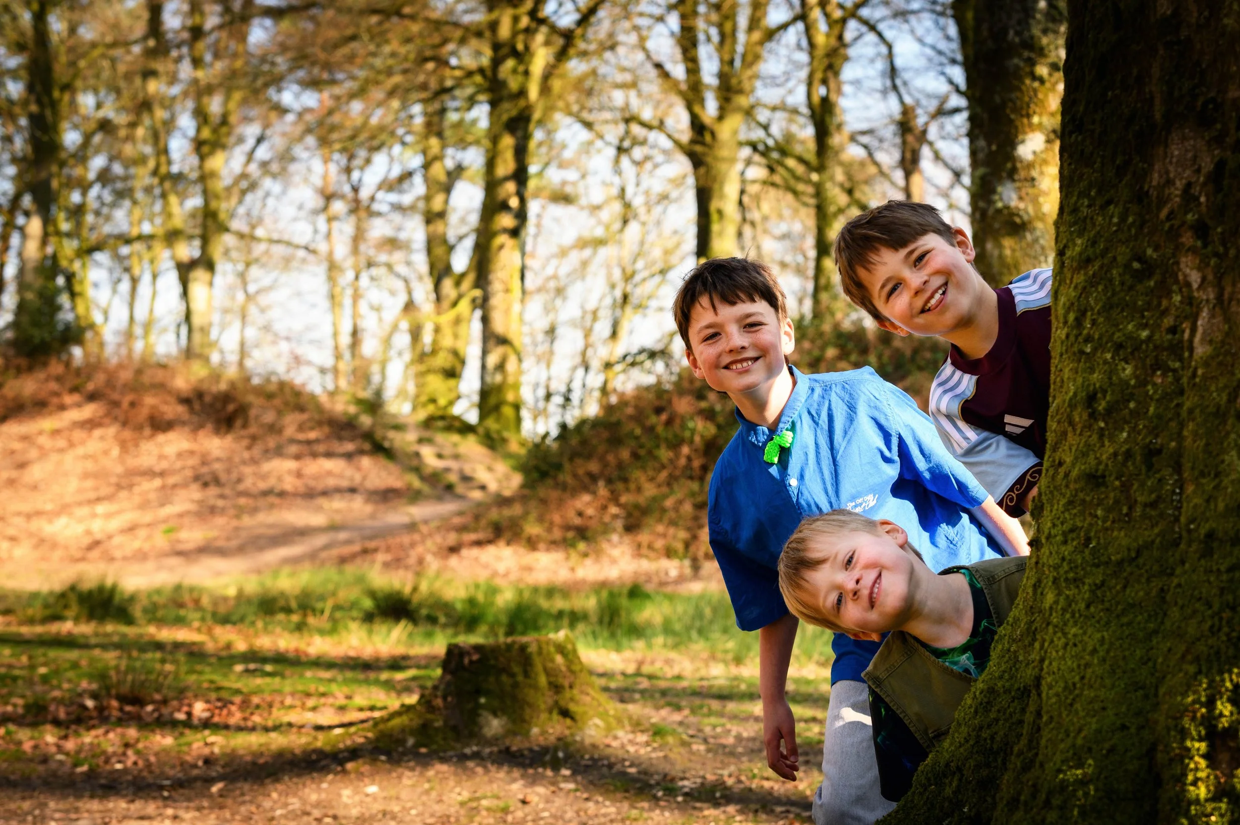 Three brothers laughing together during a woodland photo shoot