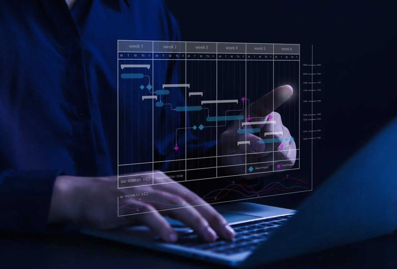 Person using a laptop with a transparent digital project management chart displayed in front of them.