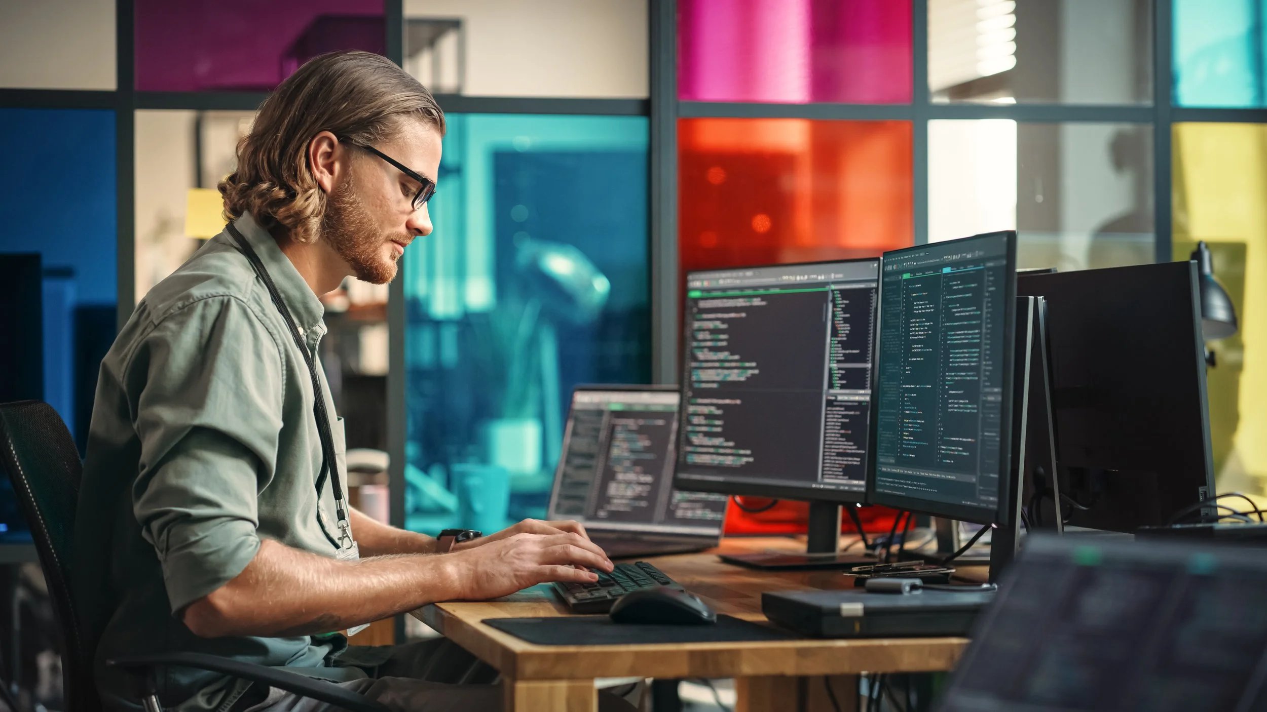 Male-Programmer-Writes-Code-On-Desktop-Computer-With-Multiple-Monitor-Setup-And-a-Laptop-Aside-In-Creative-Office.-Caucasian-Man-Developing-Mobile-App-For-Innovative-Tech-Start-Up-Online-Service.-1481183399_5120x2880.jpeg