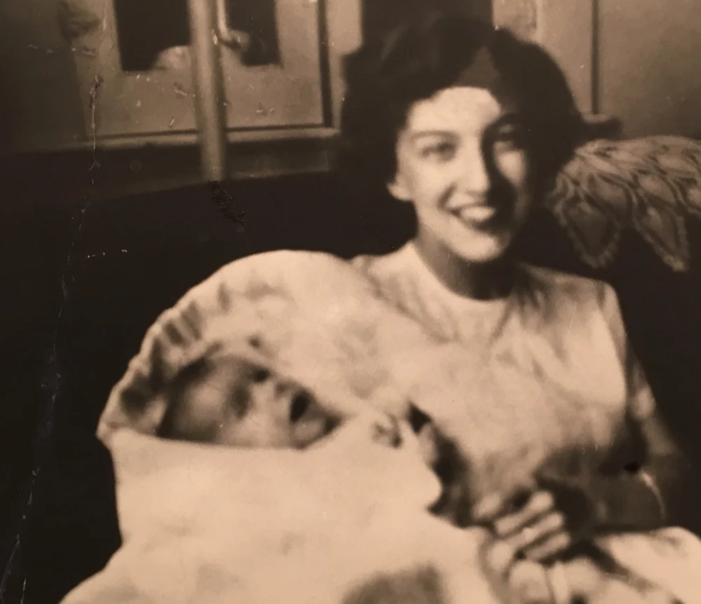 June 1952, 17-year old Joyce Hunter with her baby Bruce. (Image: A smiling young woman holding a very young baby swaddled in a white blanket).
