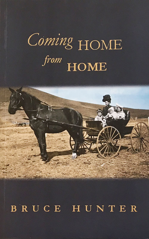 (Image: Slate-coloured cover of Coming Home From Home with colourised period photograph of a woman driving a horse and buggy with three children in it.) See family photos for a description of the original.