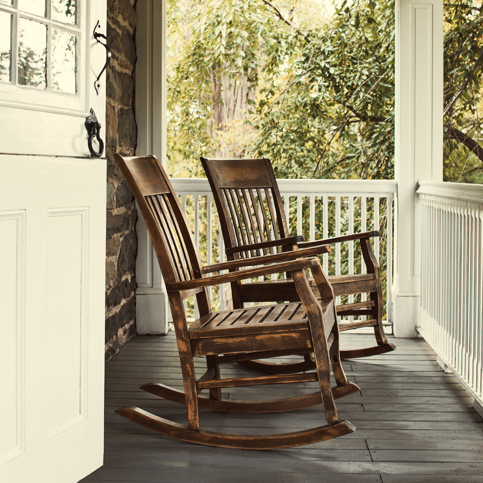 Two rocking chairs sit on a porch.