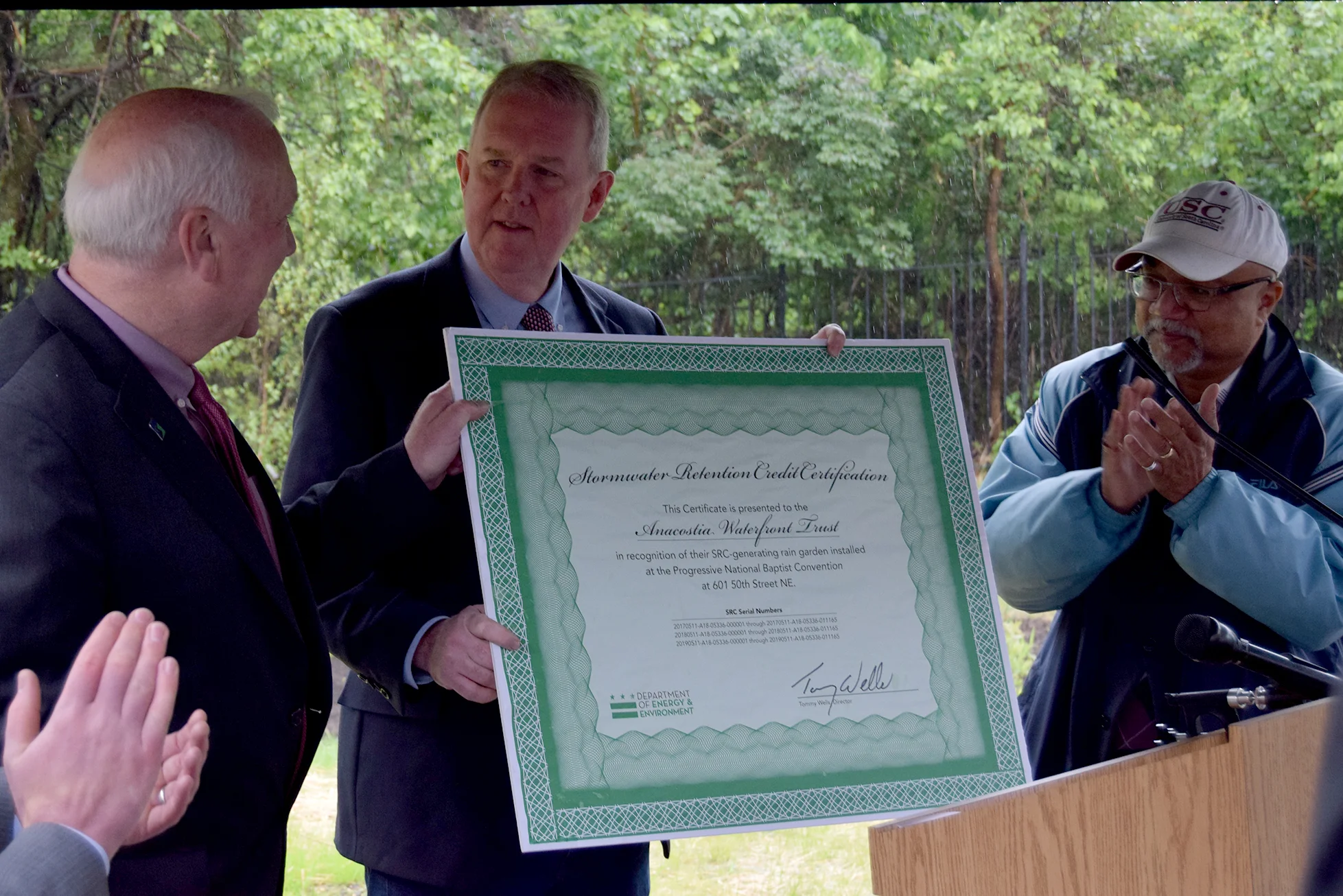 Department of Energy & Environment Director Tommy Wells presents a certificate for Stormwater Retention Credits to the Anacostia Waterfront Trust for its green infrastructure project. 
