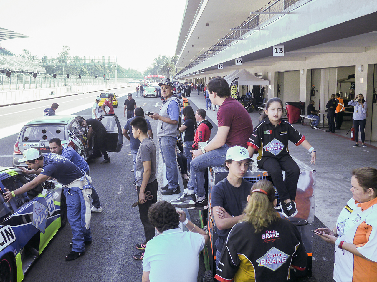 The pit lane is crowded with crews and family.