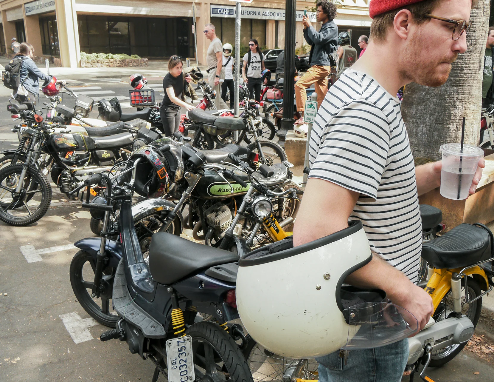 Tobias Lake looking serious with a bunch of mopeds and motorcycles. Dig the Kawi triple lurking at the curb.