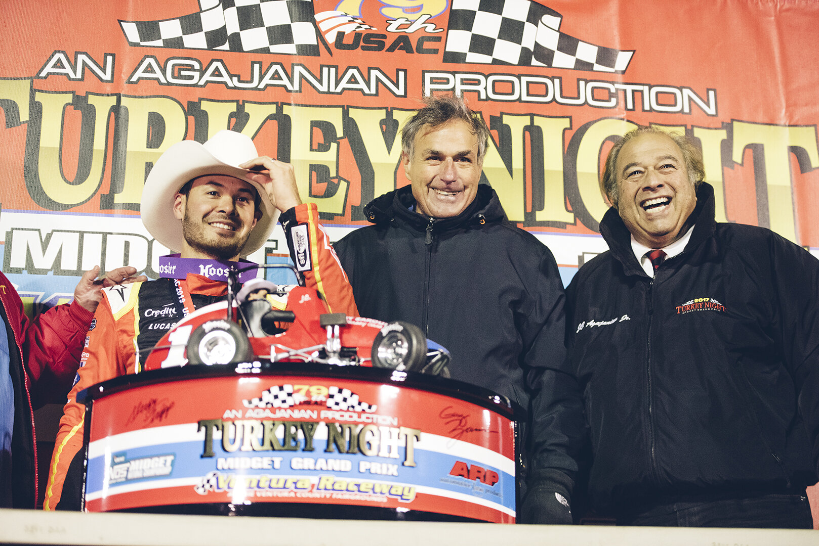  Co-grand marshall Gary Zarounian and J.C. Agajanian Jr., pose with Larson and the Turkey Night Grand Prix trophy. 
