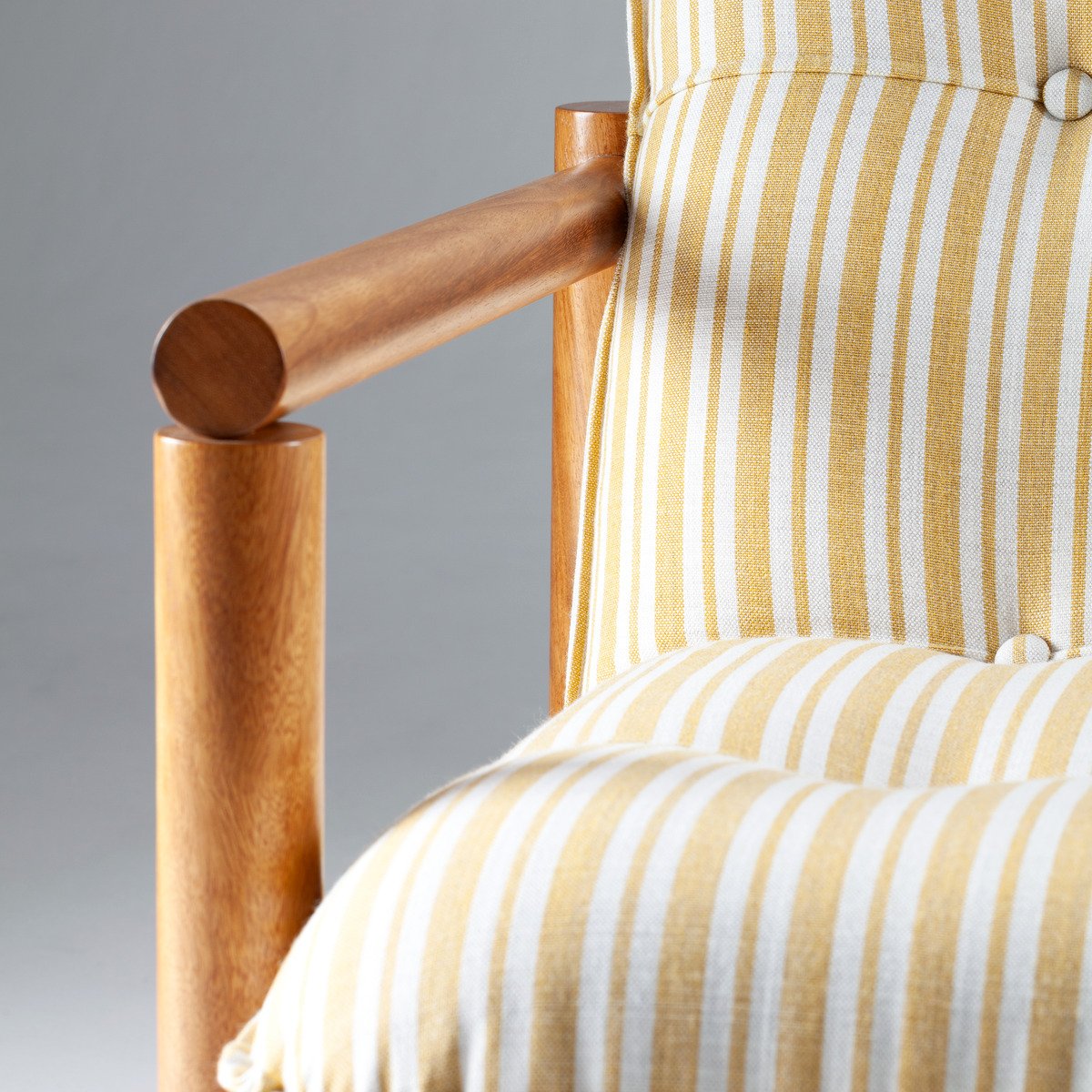 armrest-detail.avif	Macro shot of the James Armchair’s cylindrical wood armrest and the tufted texture of the striped upholstery.