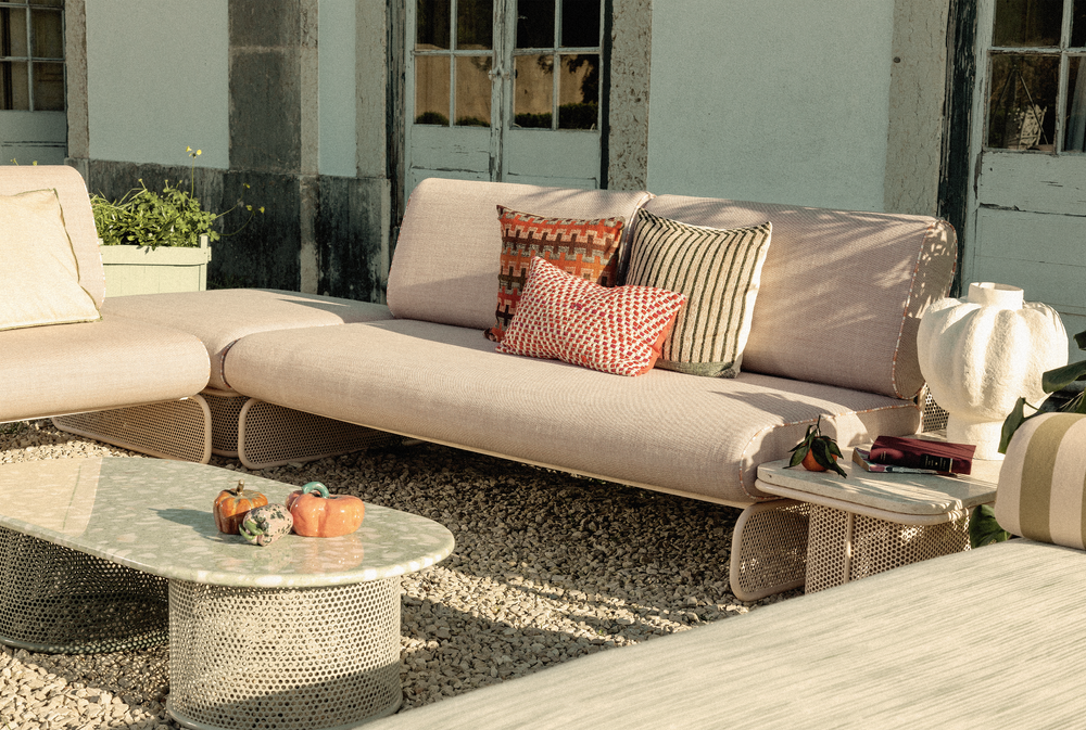 Side profile detail of the Riviera outdoor sofa showing the integrated side table armrest and textured Raja fabric upholstery