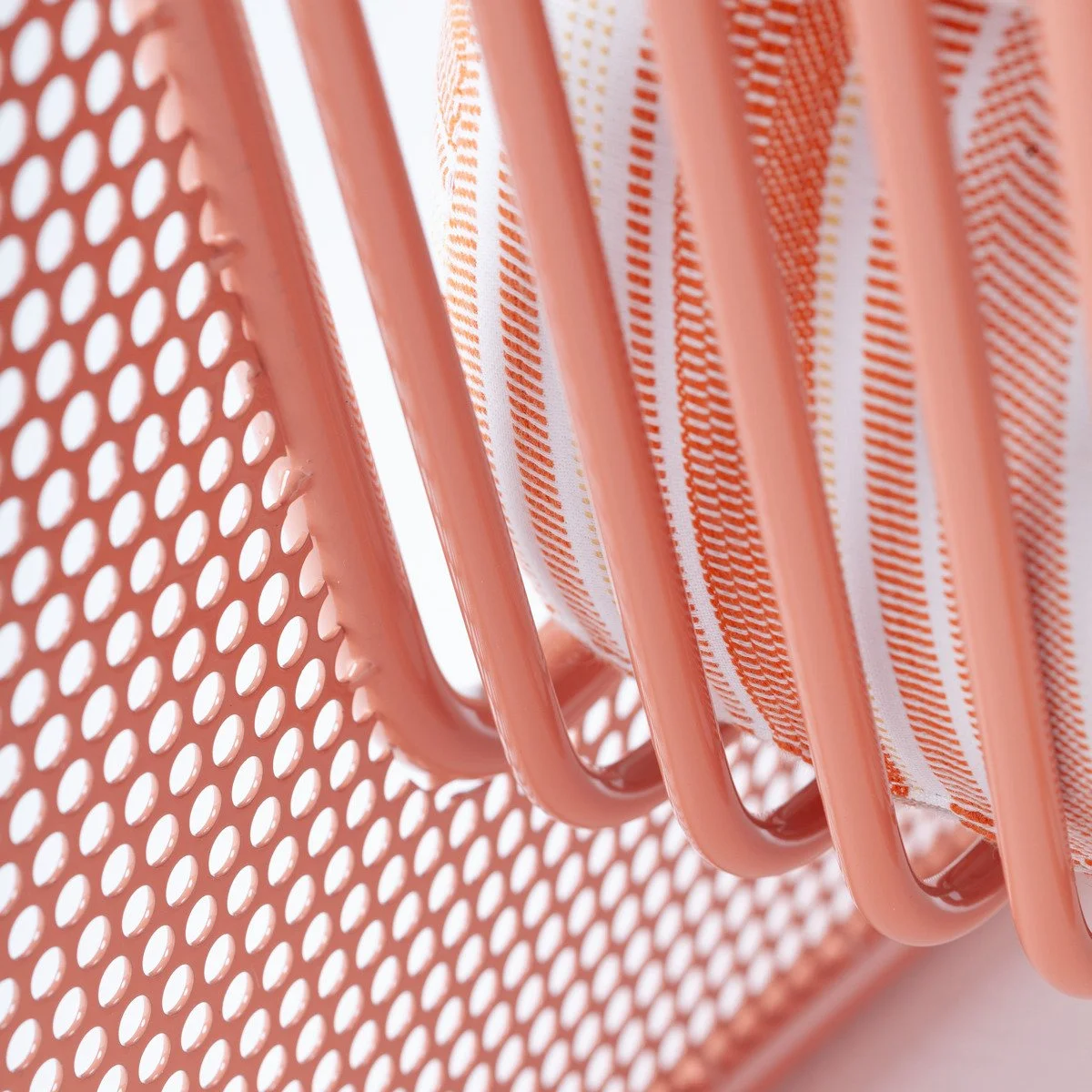 Macro shot of the perforated mesh back of the Riviera chair, emphasizing the interplay of industrial materials and soft textiles.