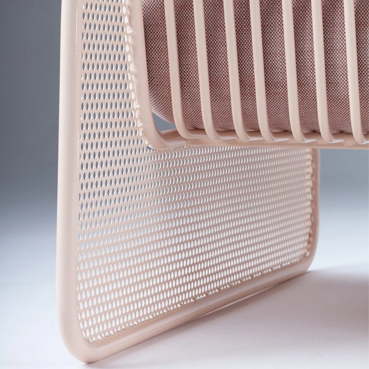Structural detail of the Riviera modular sofa's cream-lacquered steel frame, highlighting the contrast between the perforated base and solid vertical bars.