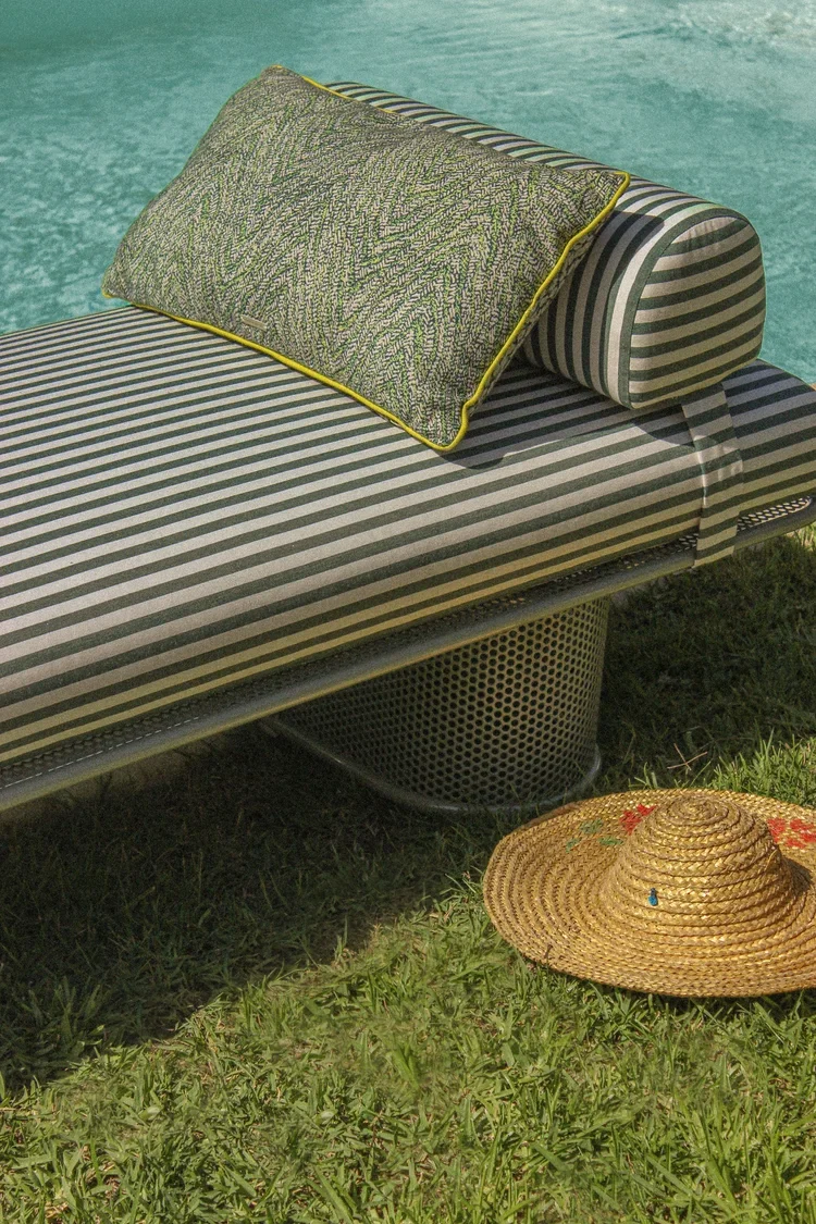 Striped Riviera outdoor lounge chair with cushion placed beside a swimming pool on grass