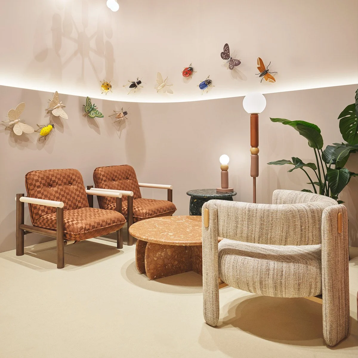 Designer showroom display featuring a pair of James Armchairs in copper geometric fabric styled with sculptural lighting and stone tables.