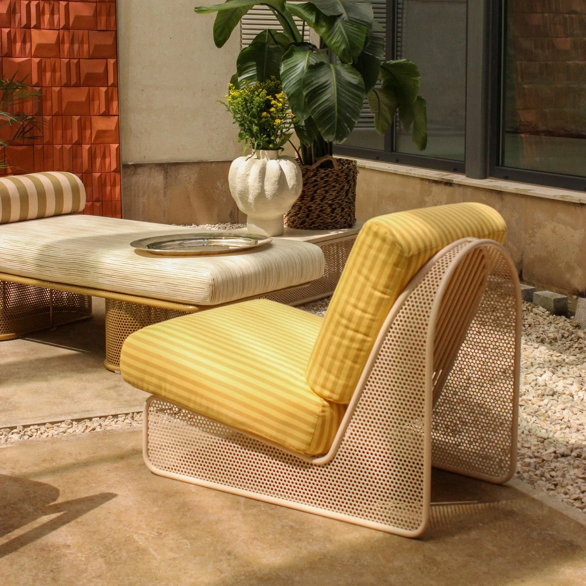 Lifestyle view of the Riviera Chaise and Armchair in a curated garden patio, embodying the French Caribbean design aesthetic.