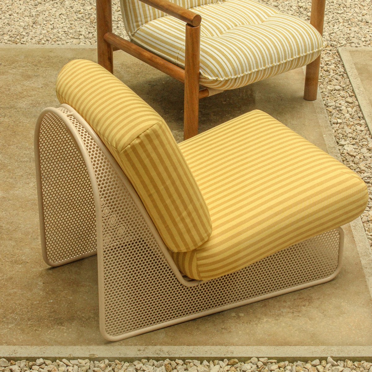 Top-down view comparing the wood-frame James Armchair and the metal-frame Riviera Armchair in a modern gravel courtyard.