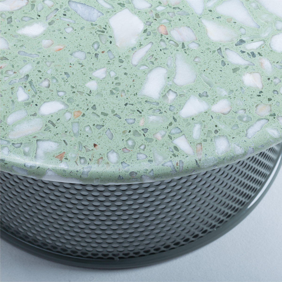 Close-up of green terrazzo surface with natural stone fragments on coffee table