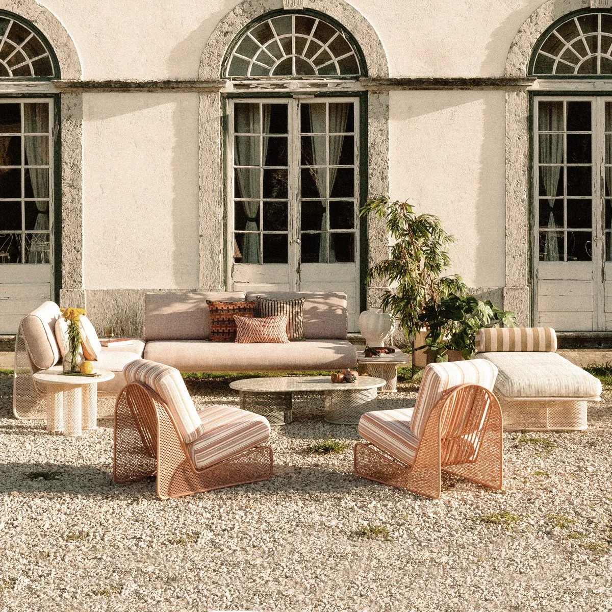 Complete Riviera outdoor furniture set including lounge chairs, modular sofa, and daybed arranged outside a traditional European villa.