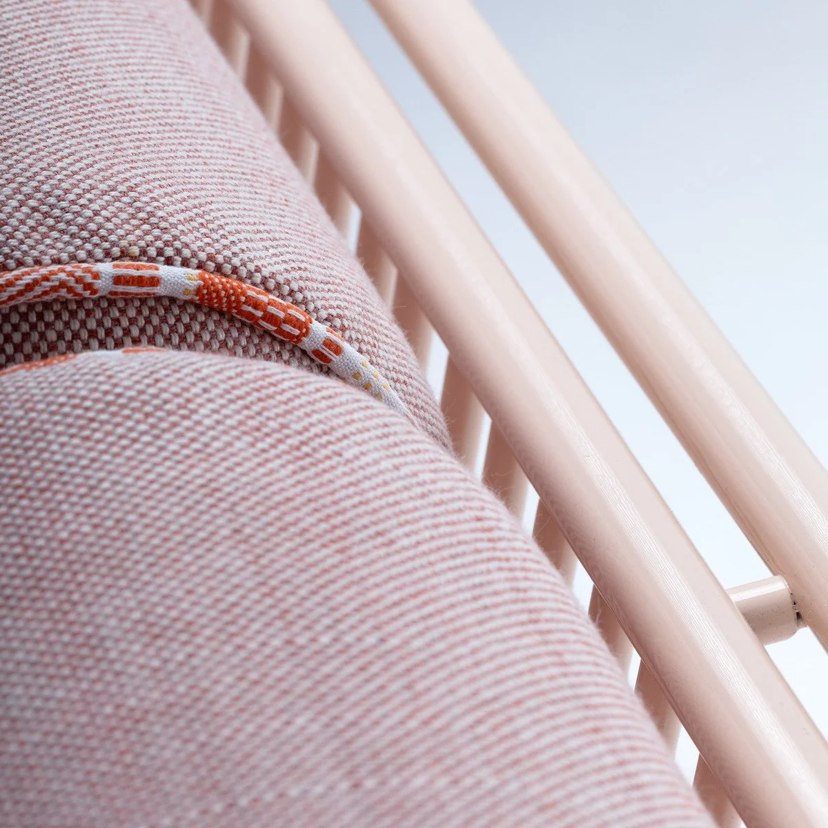 Close-up detail of the Riviera modular sofa featuring artisanal orange and white braided piping on neutral performance fabric.