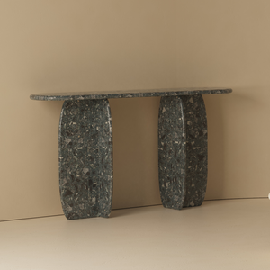 Dark stone console table placed against a wall, highlighting its architectural form and modern outdoor design appeal.