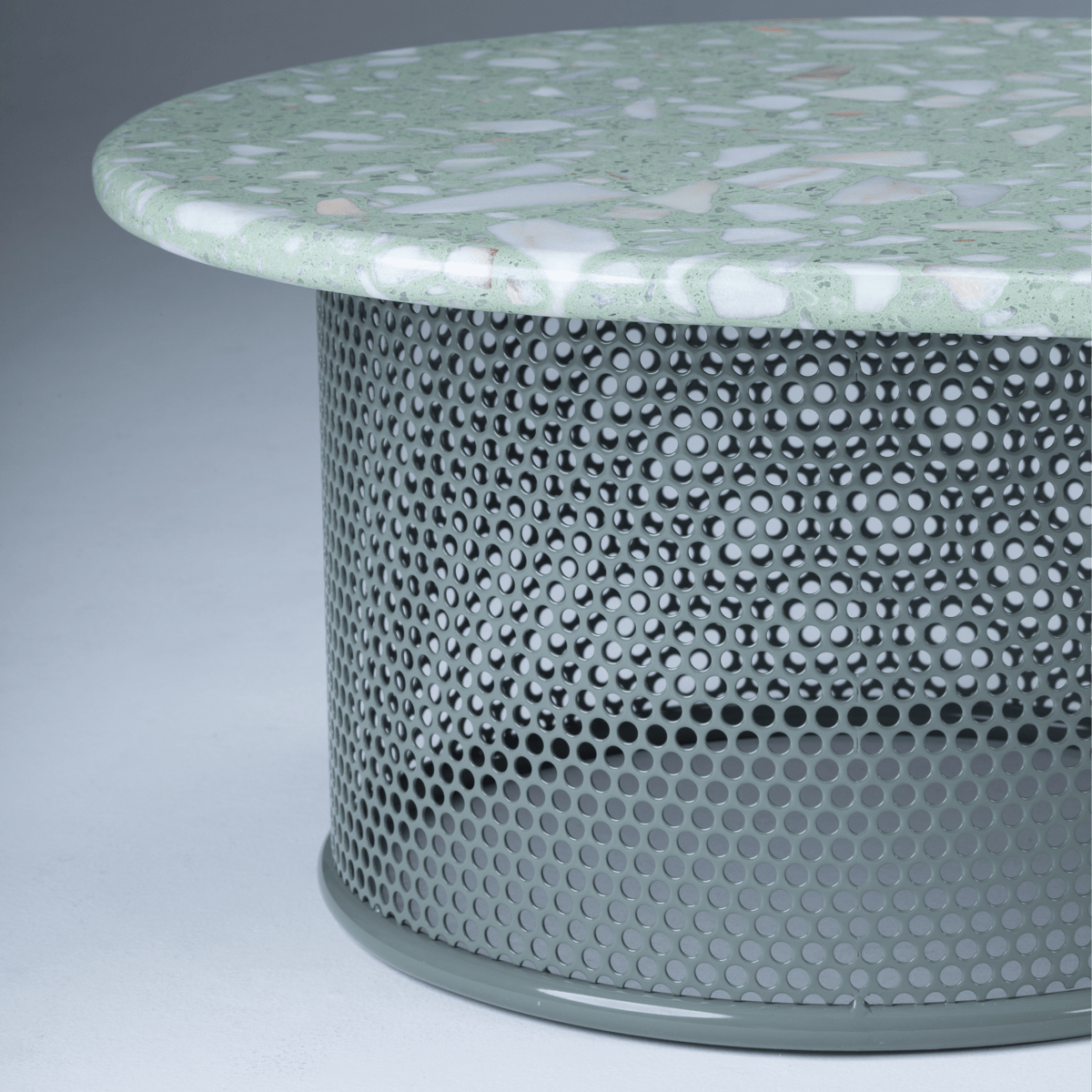Green terrazzo coffee table detail showing rounded edge and perforated metal base