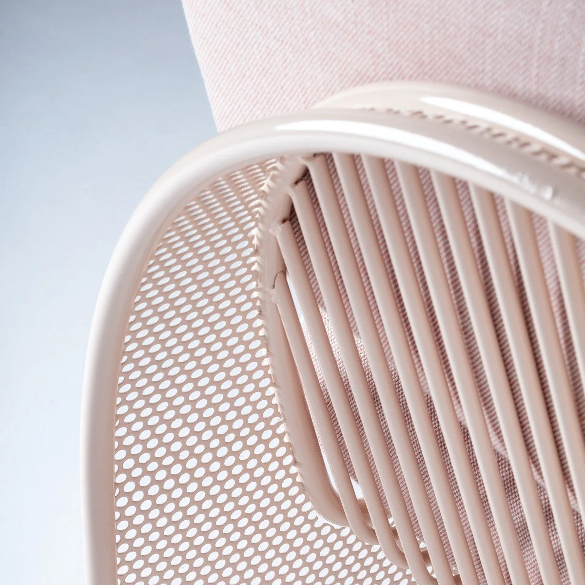 Macro view of the Riviera sofa's cream-lacquered stainless steel frame, showing the signature laser-cut perforated pattern and vertical support bars.