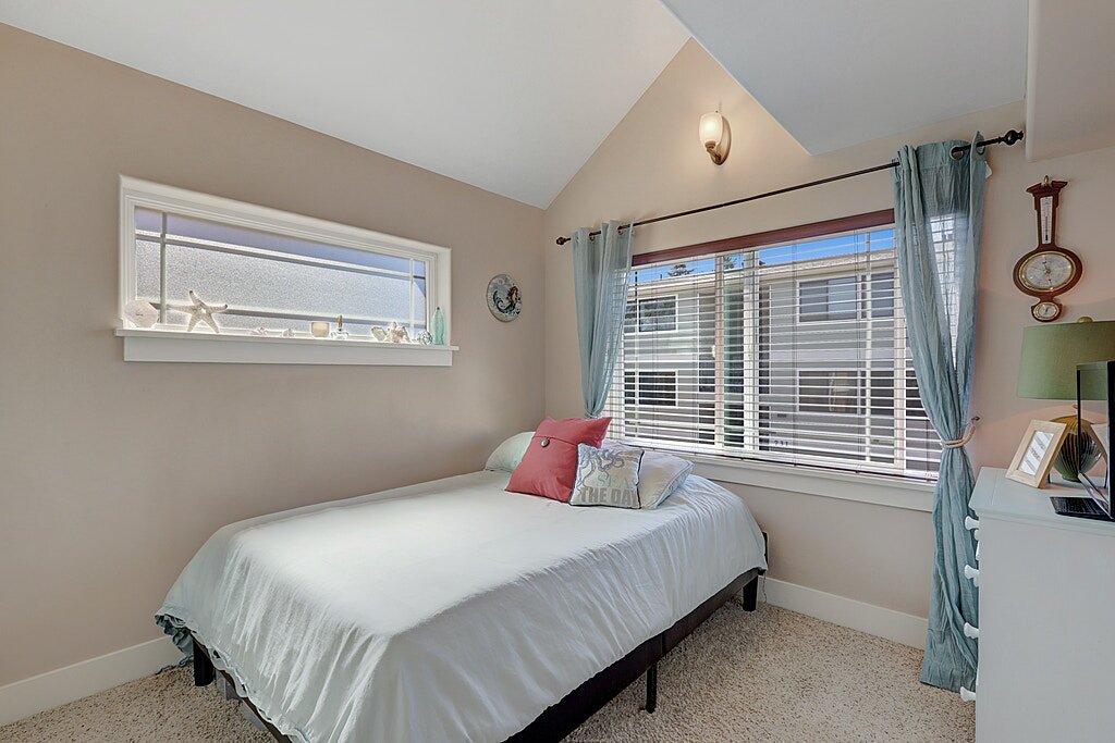  A roomy guest room with two windows and a double closet. The ceilings vault in the middle of the room, giving an airy quality to this bedroom. 