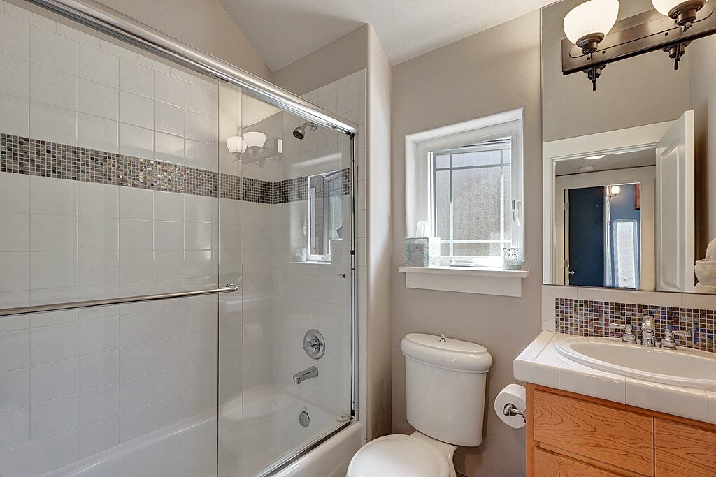  The full guest bath with a glass door and a ceramic tile surround. 