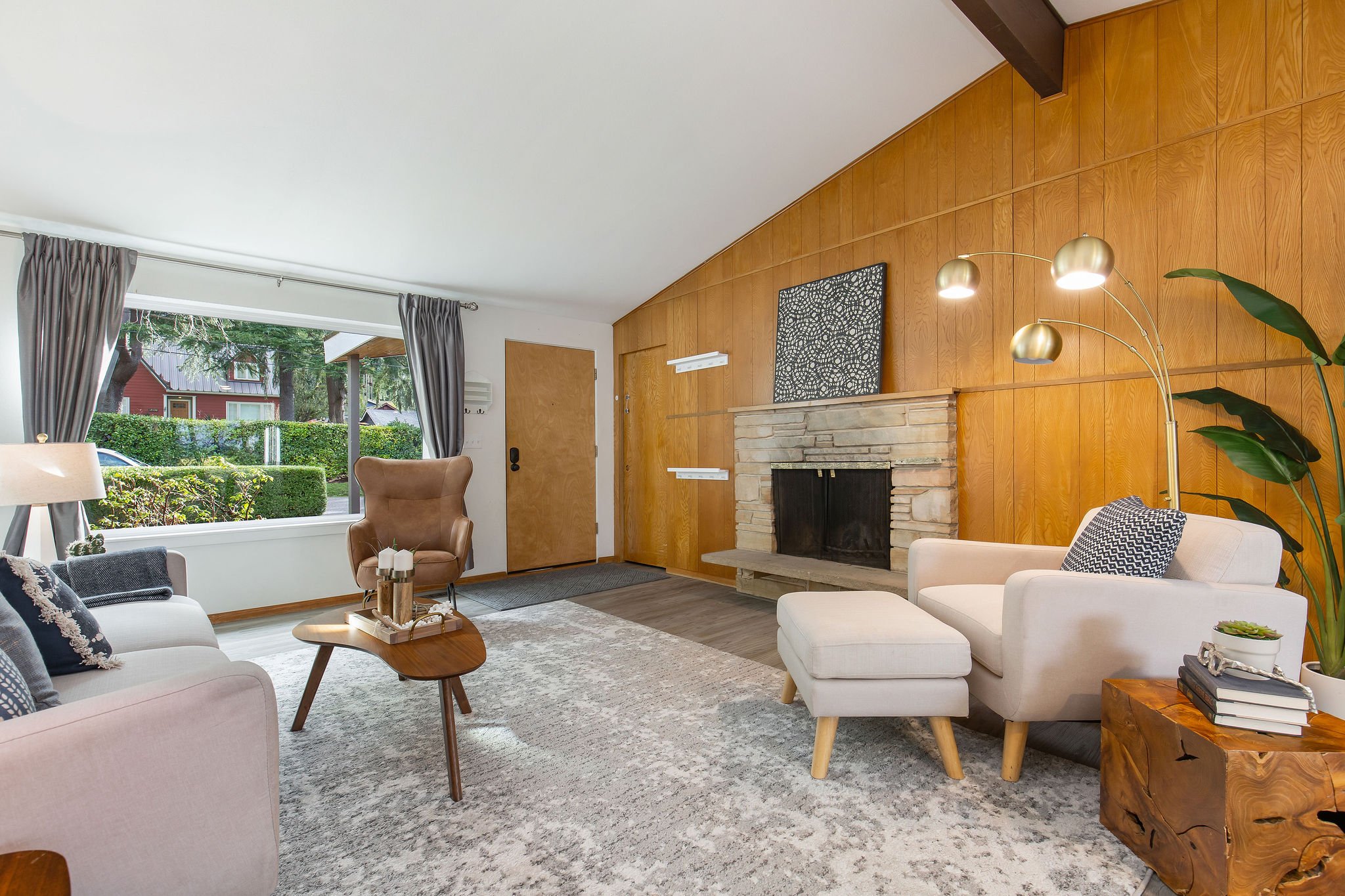   image description: interior of living room with couch, chair with ottoman, stone fireplace, and large window 