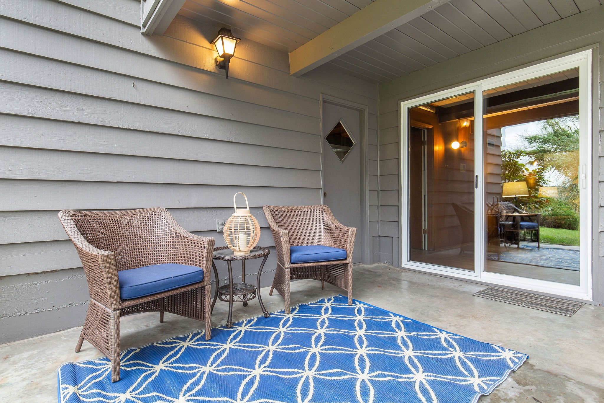  image description: exterior of patio with whicker chairs and rug 