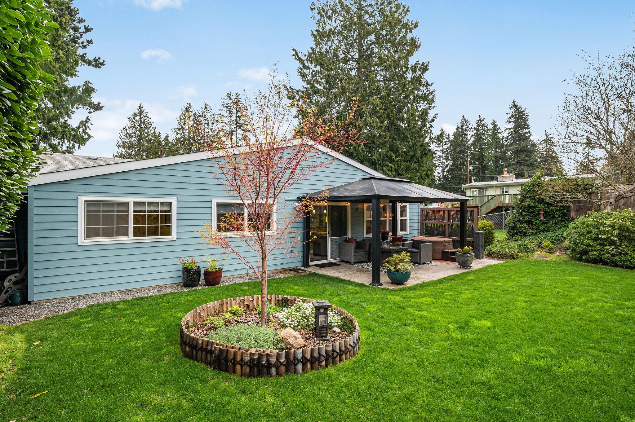  image description: exterior of one story blue house with patio with awning and patio furniture 