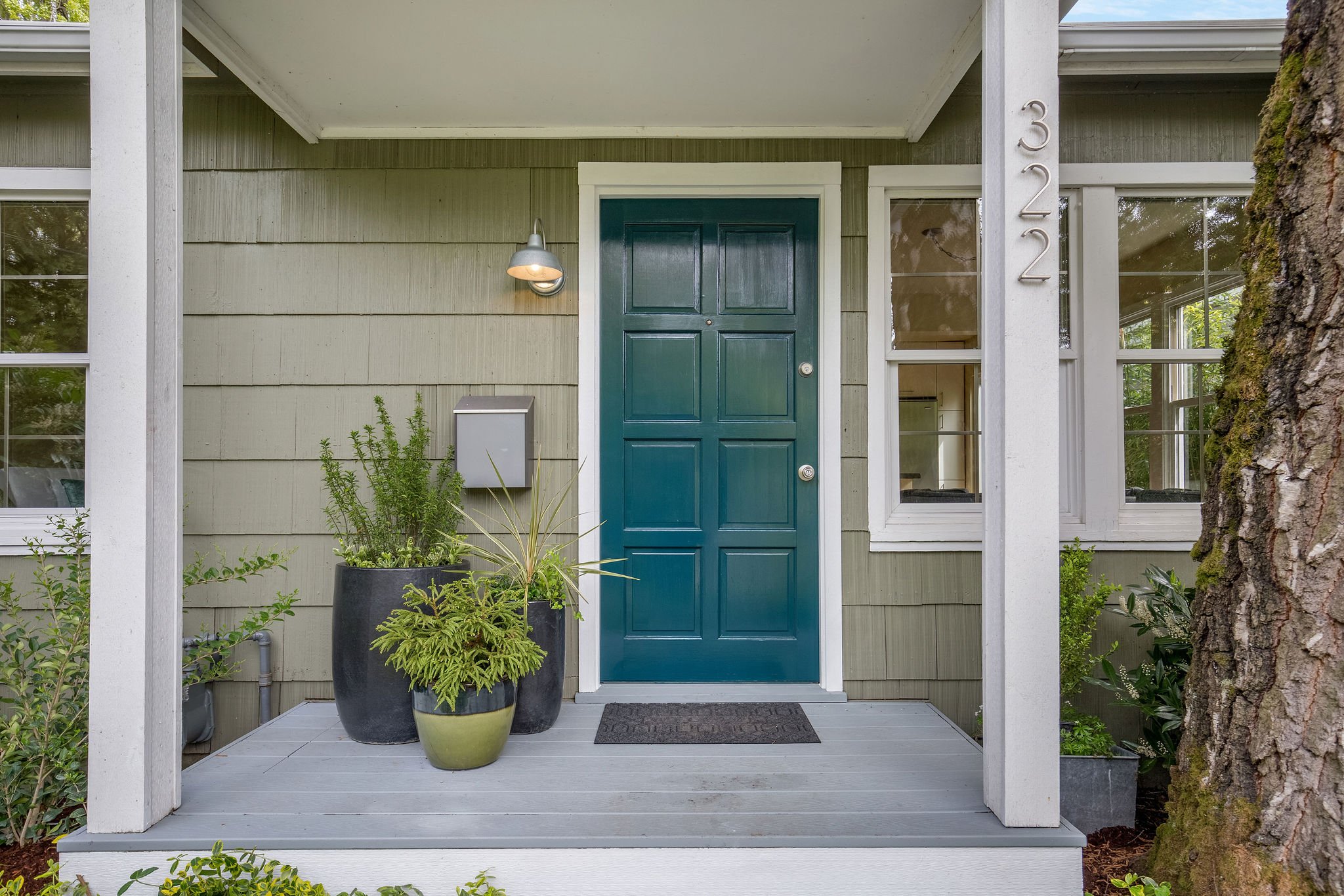  image description: exterior of green one story cottage with view of blue front door 