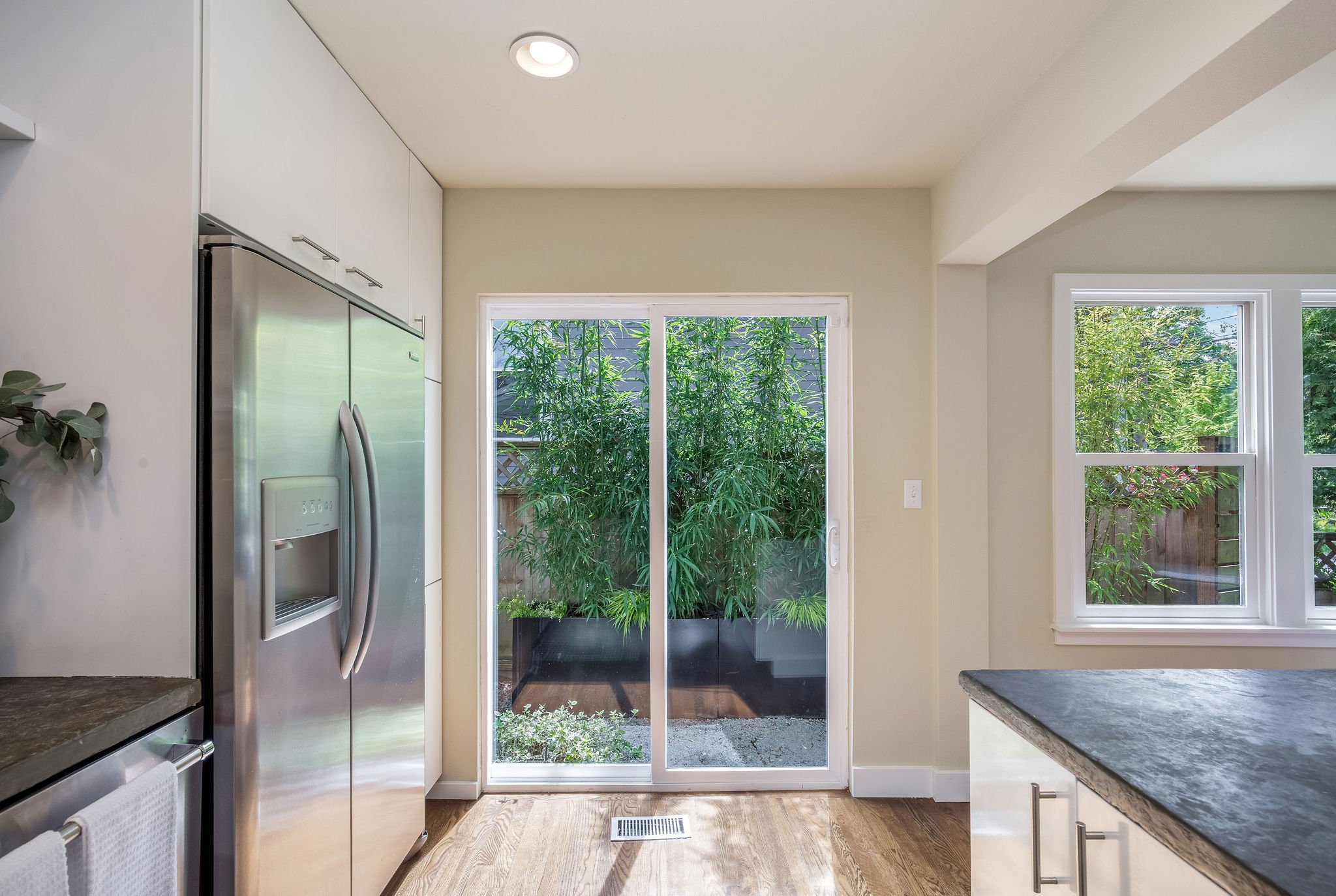  image description: interior kitchen with connected island, hardwoods, brown countertops and sliding glass door 
